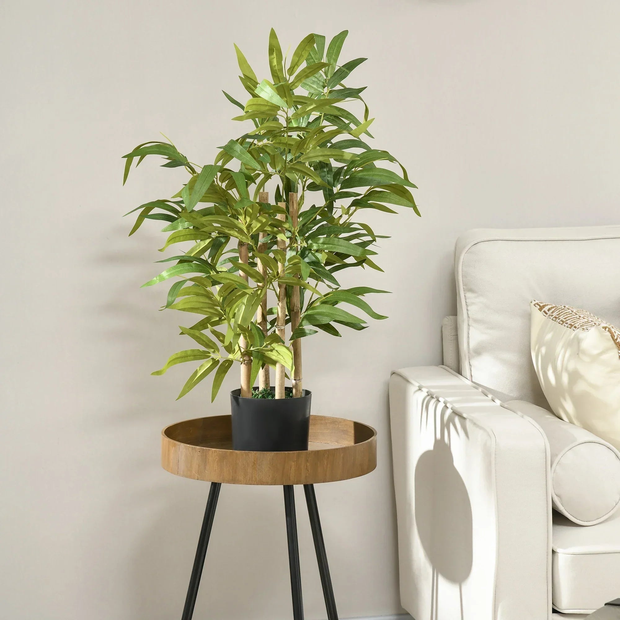 Artificial green plant in black pot on wooden side table next to white sofa in modern living room