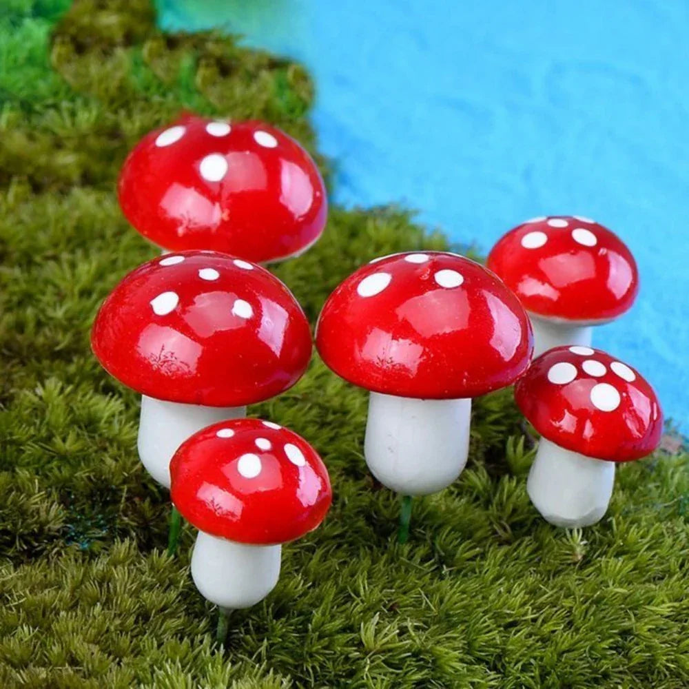 Decorative red and white spotted mushroom garden ornaments on green moss with blue background