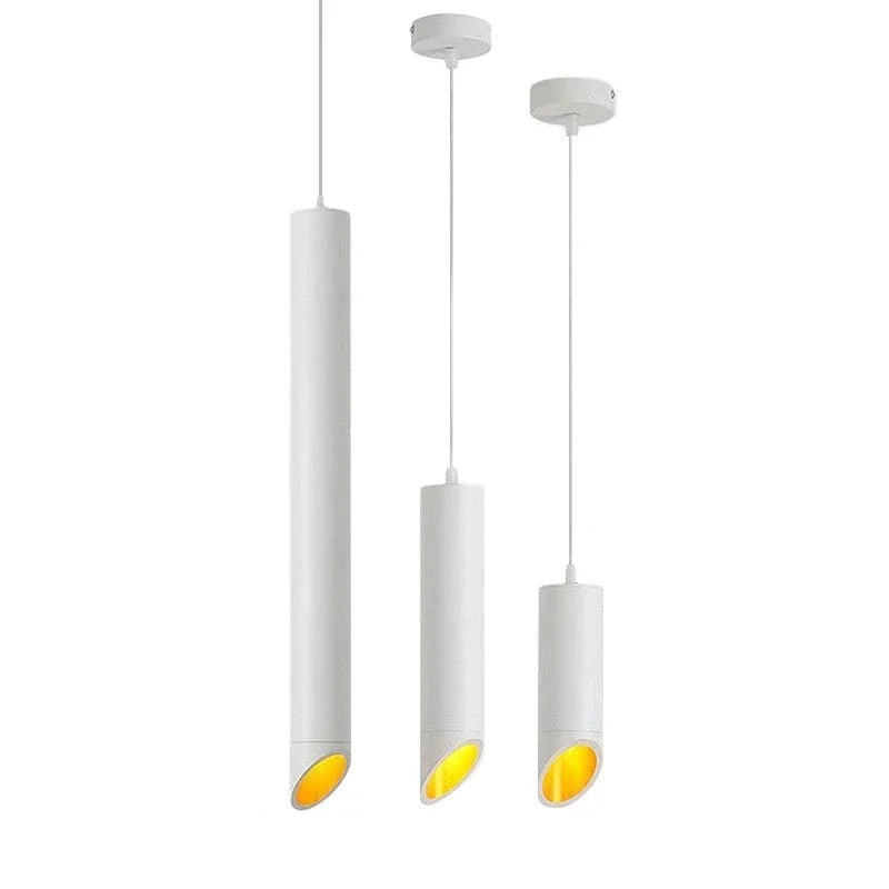 Three modern white cylindrical pendant lights with warm yellow glow, hanging at different lengths