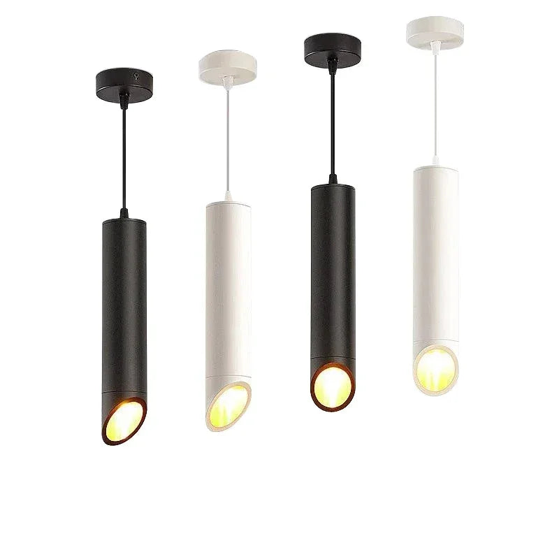 Four modern cylindrical pendant ceiling lights in black and white with angled warm LED illumination