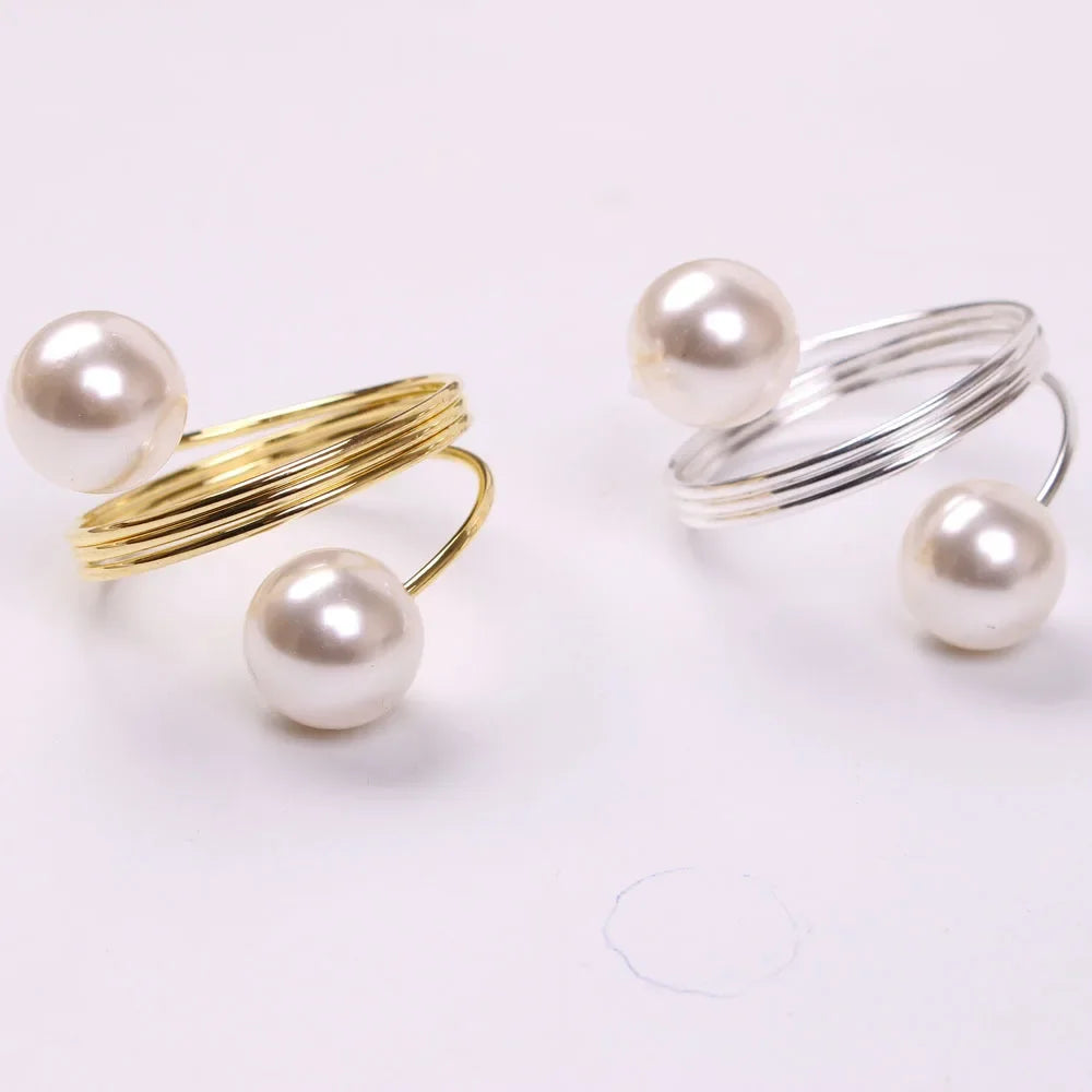 Two modern open rings with large white pearls, one with gold band and the other with silver band on white background
