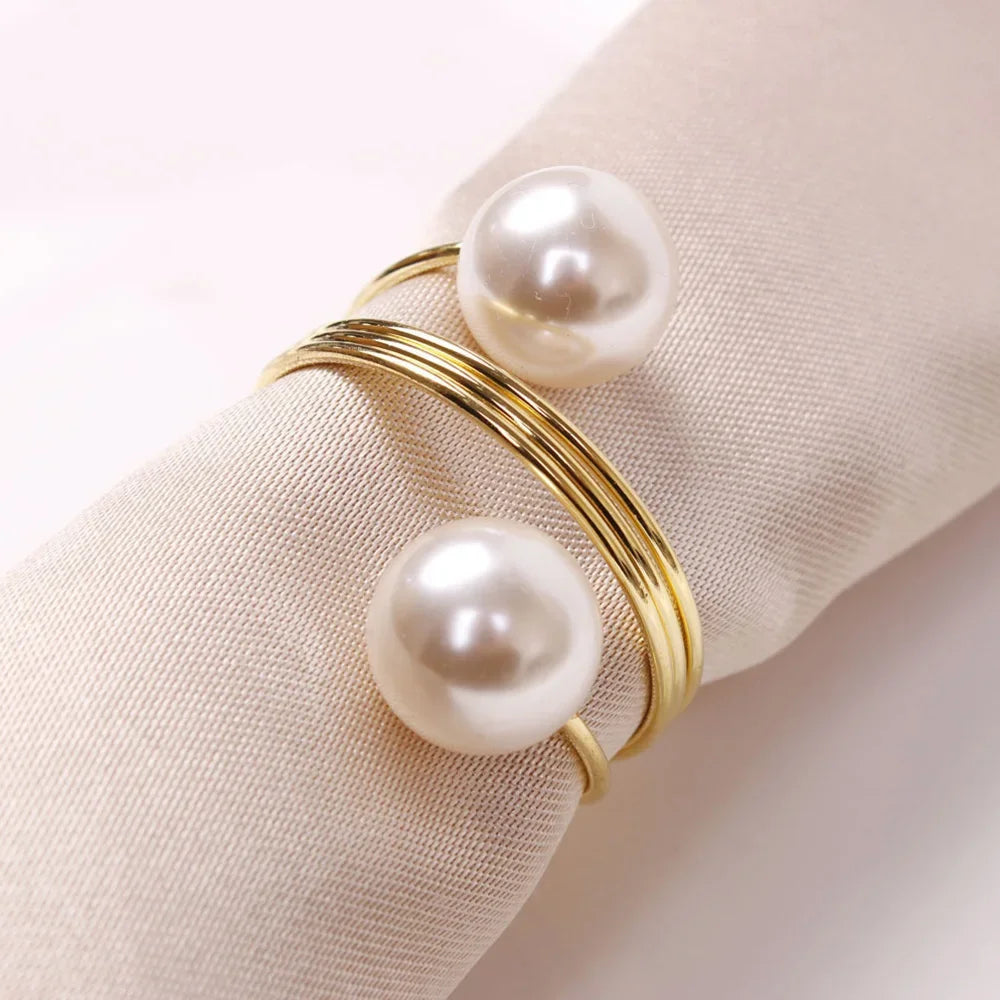 Elegant gold napkin ring with two large white pearls on beige fabric for stylish table setting