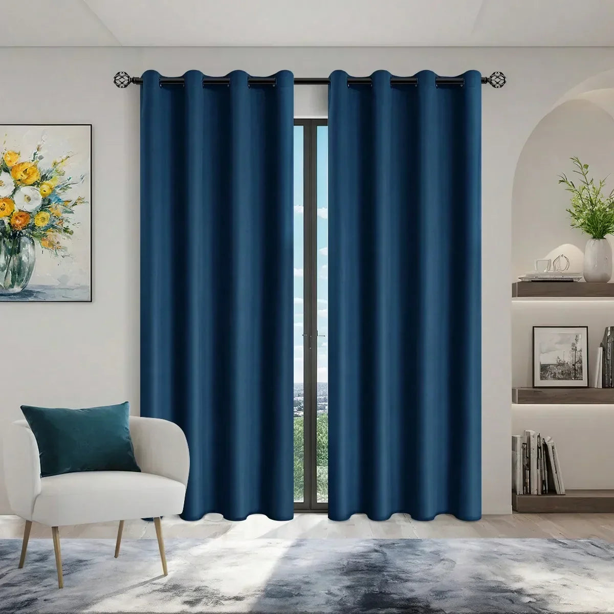 Modern living room with deep blue blackout curtains on window, white armchair with blue pillow, floral painting, and minimalist shelving