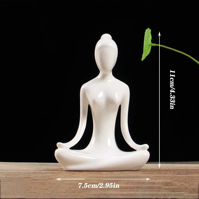 White ceramic yoga meditation statue sitting cross-legged on wooden surface with black background