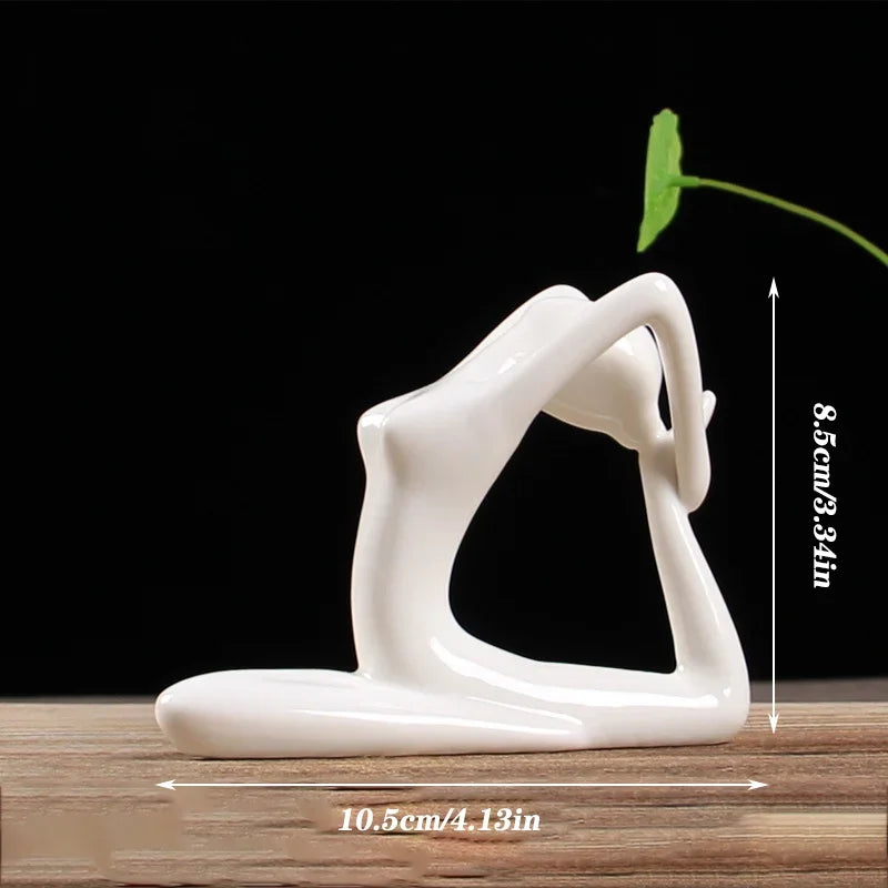 White ceramic yoga pose figurine vase with green leaf, 8.5cm tall on wooden surface